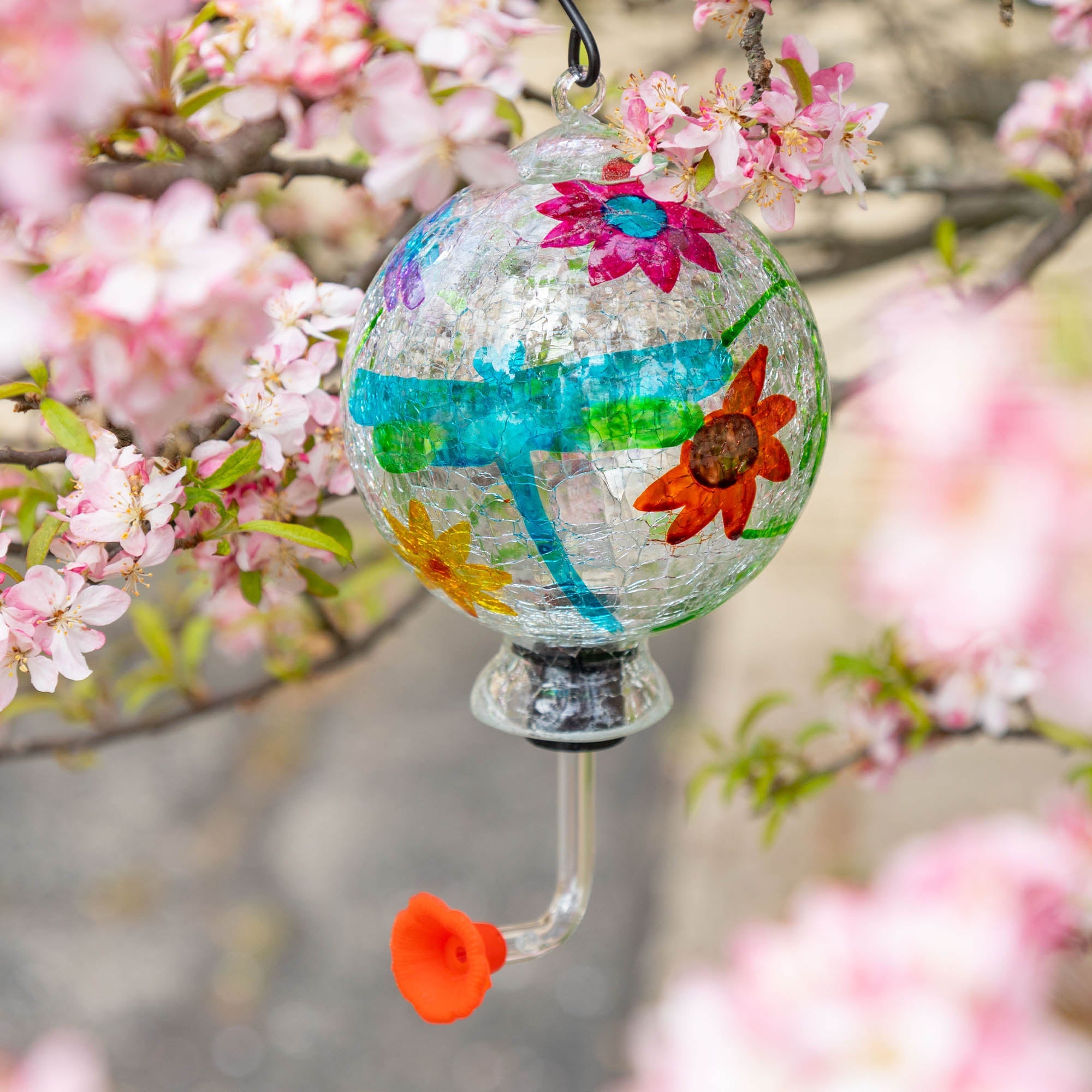Hand-painted glass hummingbird feeder with blue-green ribbon design and orange flower