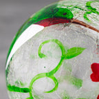 Close-up of hand-painted glass hummingbird feeder with green and red details