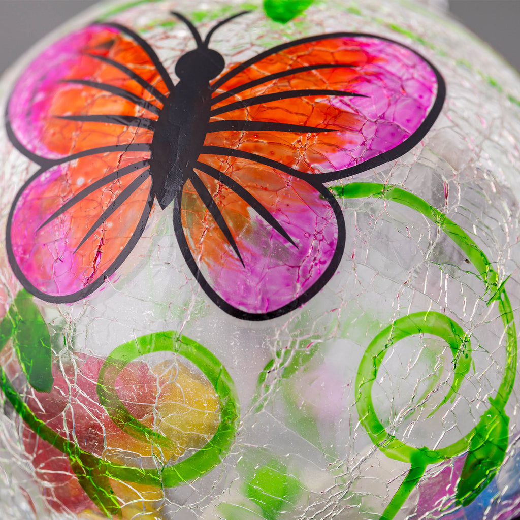 Close-up hand-painted glass hummingbird feeder with large multicolor butterfly wings