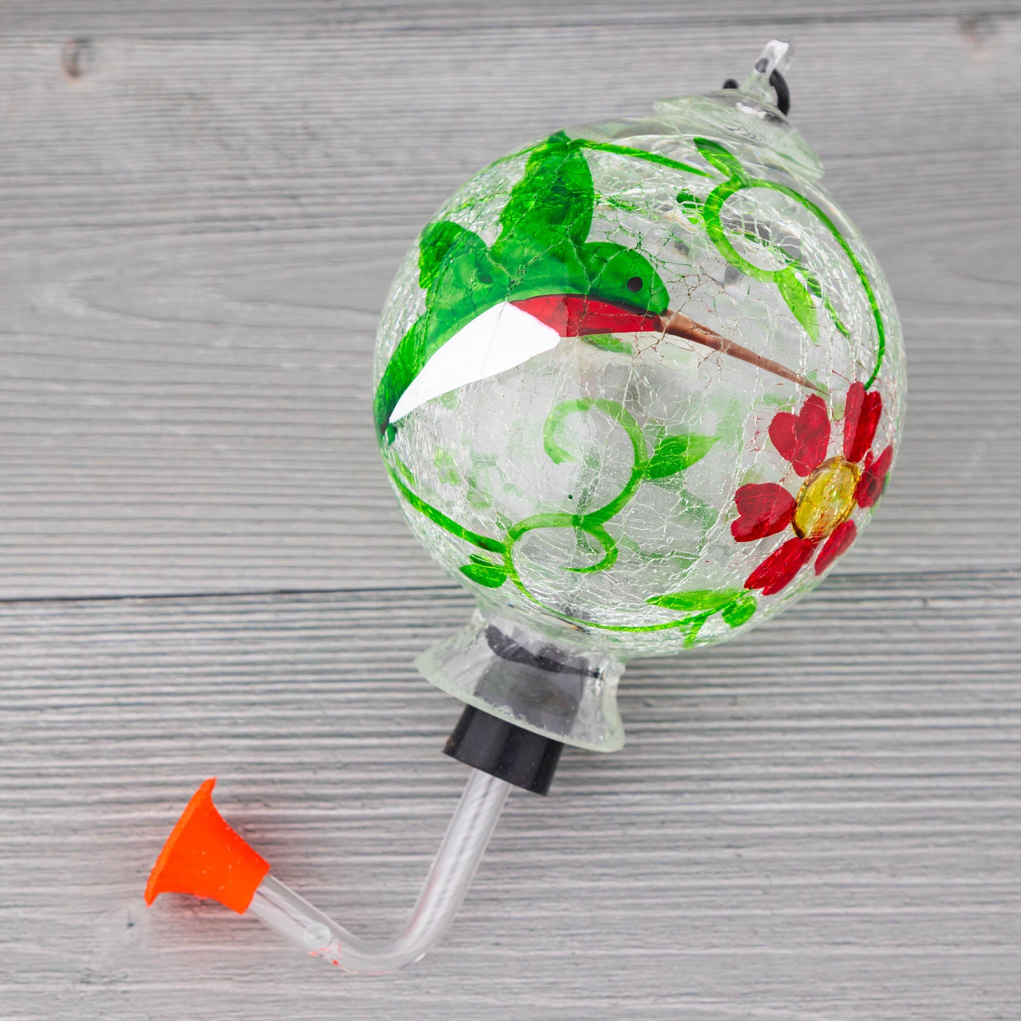 Hand-painted glass hummingbird feeder globe with green bird design, red flowers, clear tube