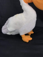 White plush pelican toy close-up showing orange webbed feet and gray wing tips