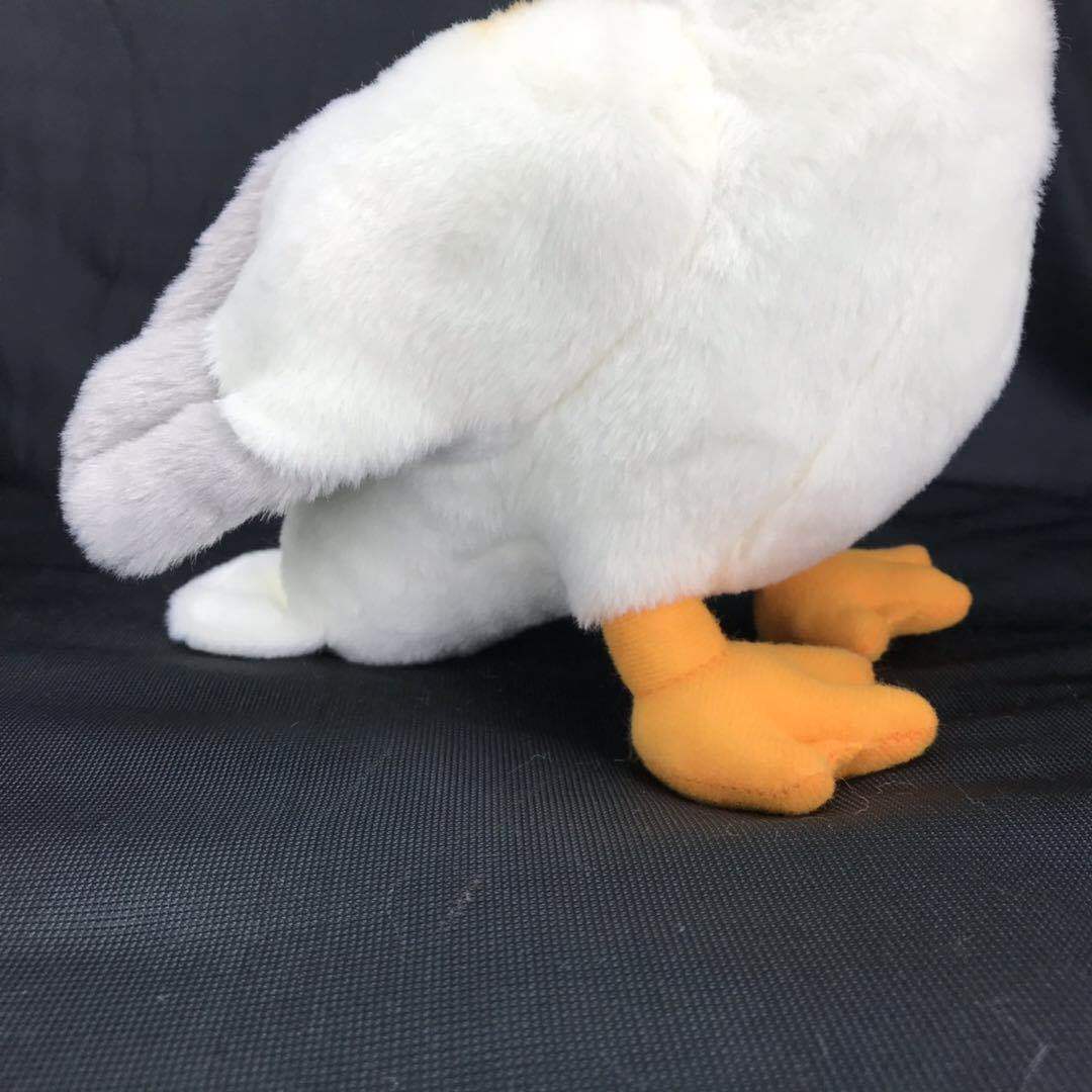 White plush pelican toy side view with gray wing tips and orange webbed feet