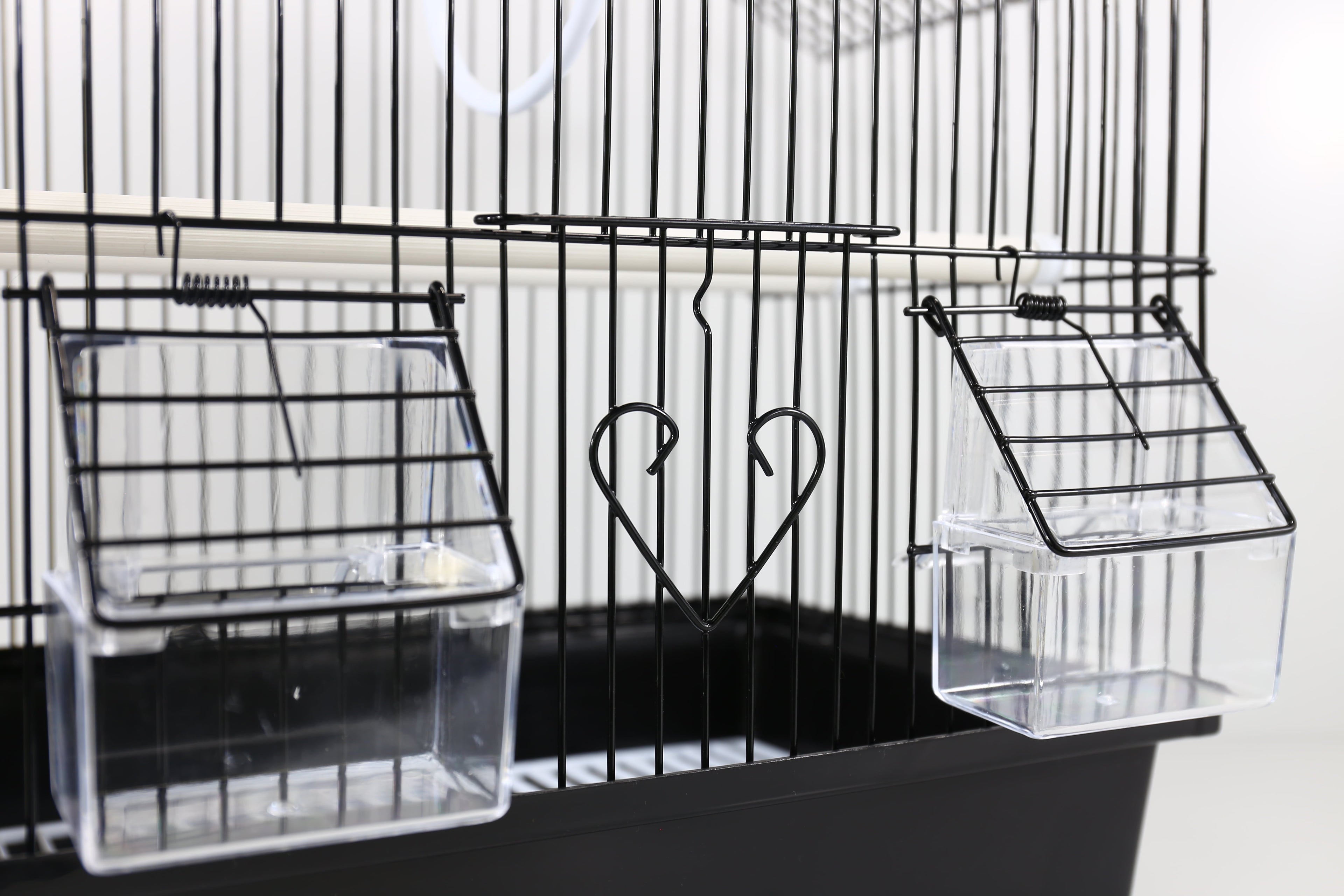 Clear front trays attached to a black wire small bird cage with roof and perches