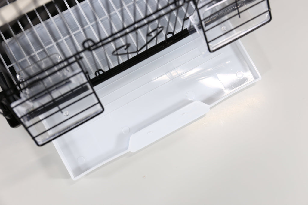 Clear plastic tray under a black wire small bird cage, viewed from above