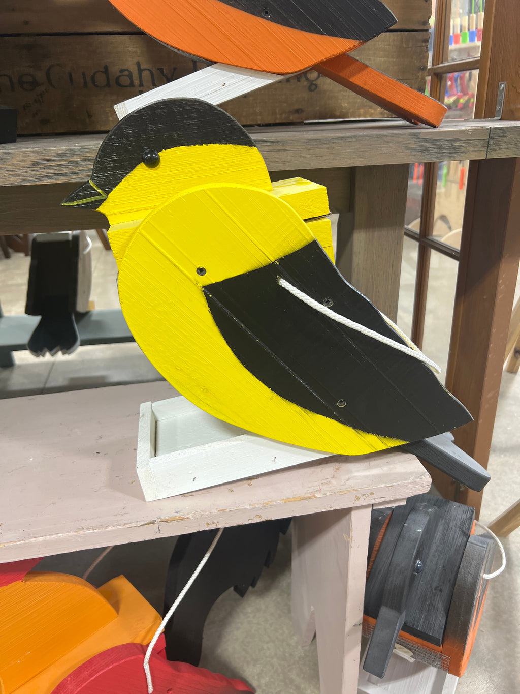 Close-up of a yellow and black wooden hanging wild bird feeder with mesh body