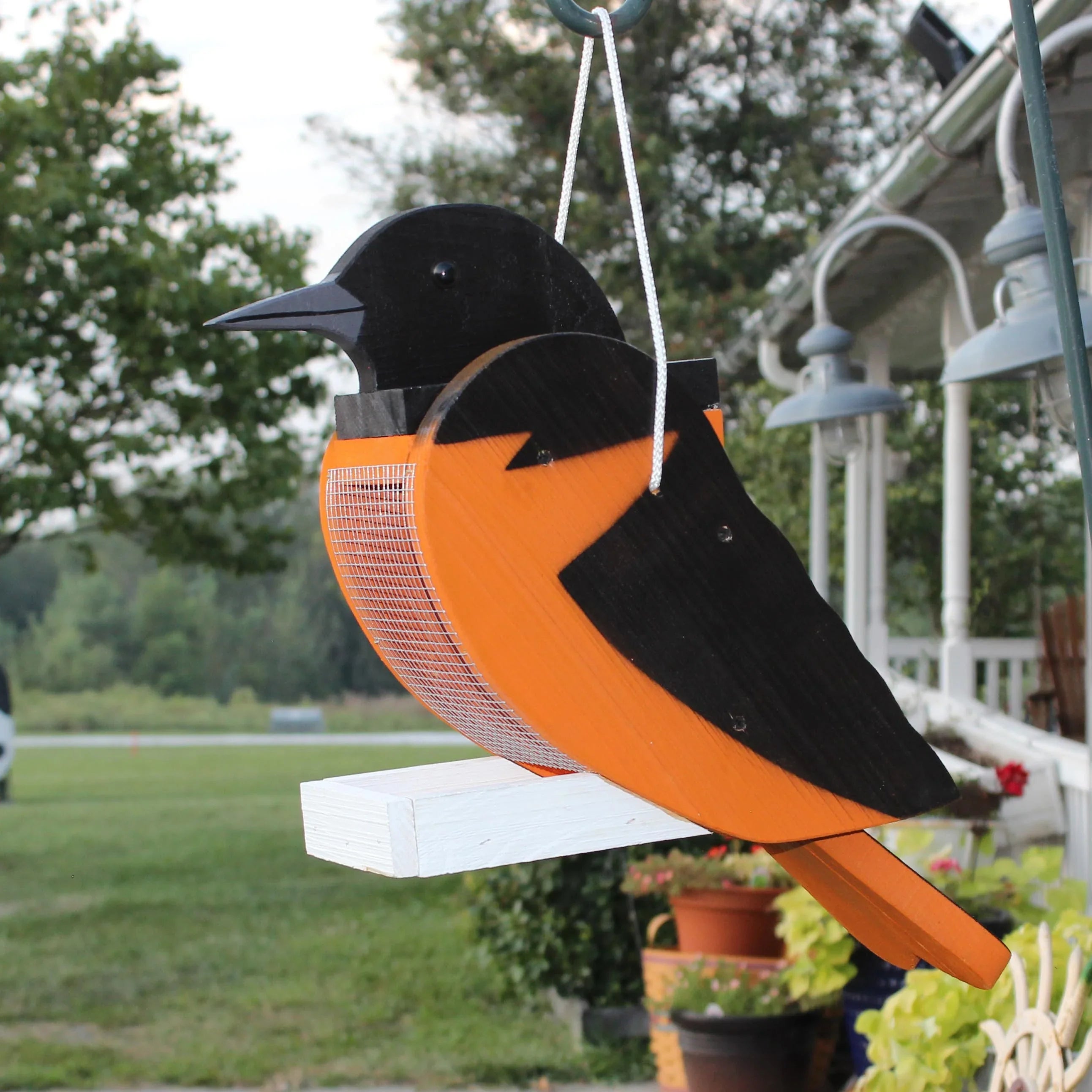 Wooden hanging wild bird feeder shaped like a dark bird with orange accents and mesh body