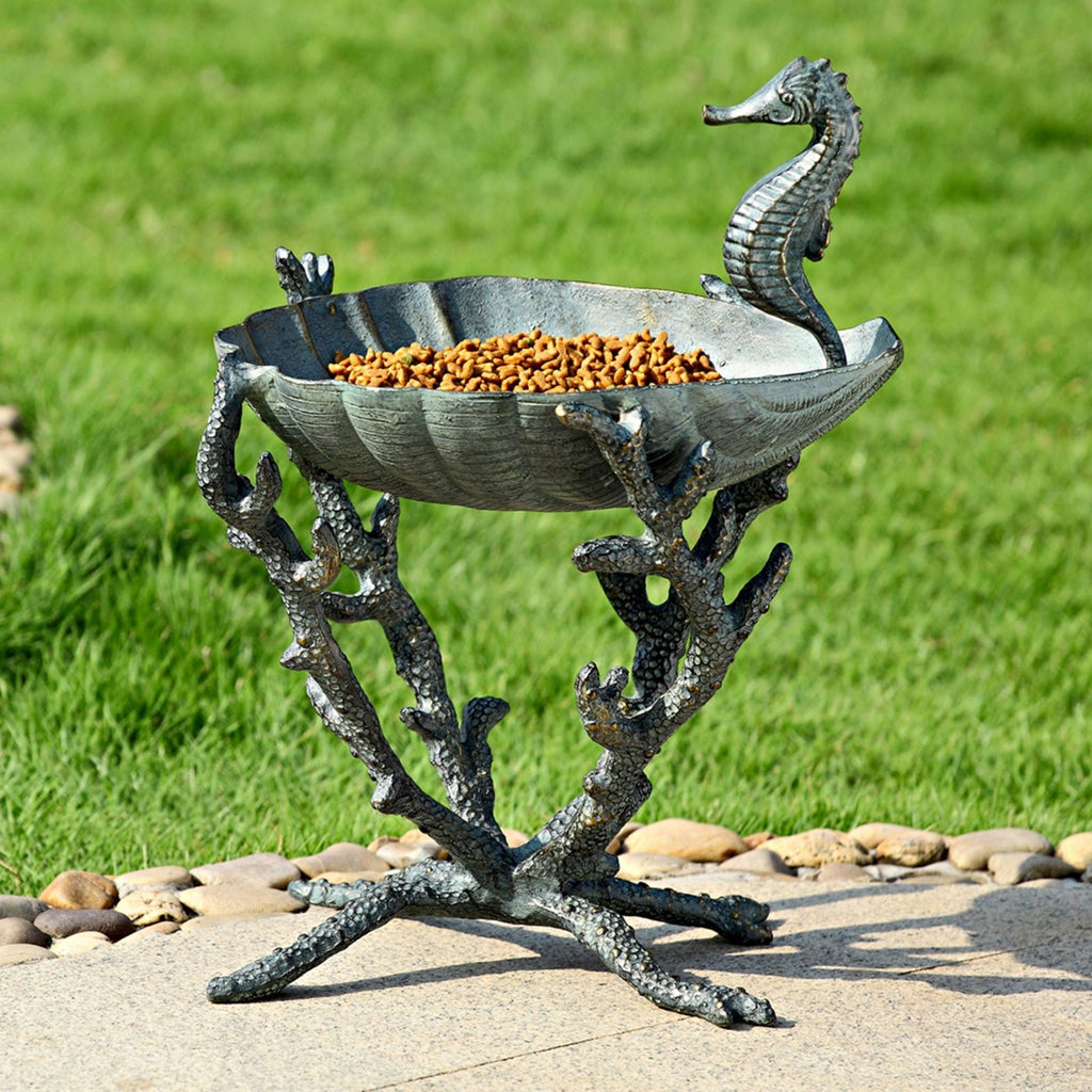 Cast aluminum seahorse birdbath with raised basin, filled with orange birdseed