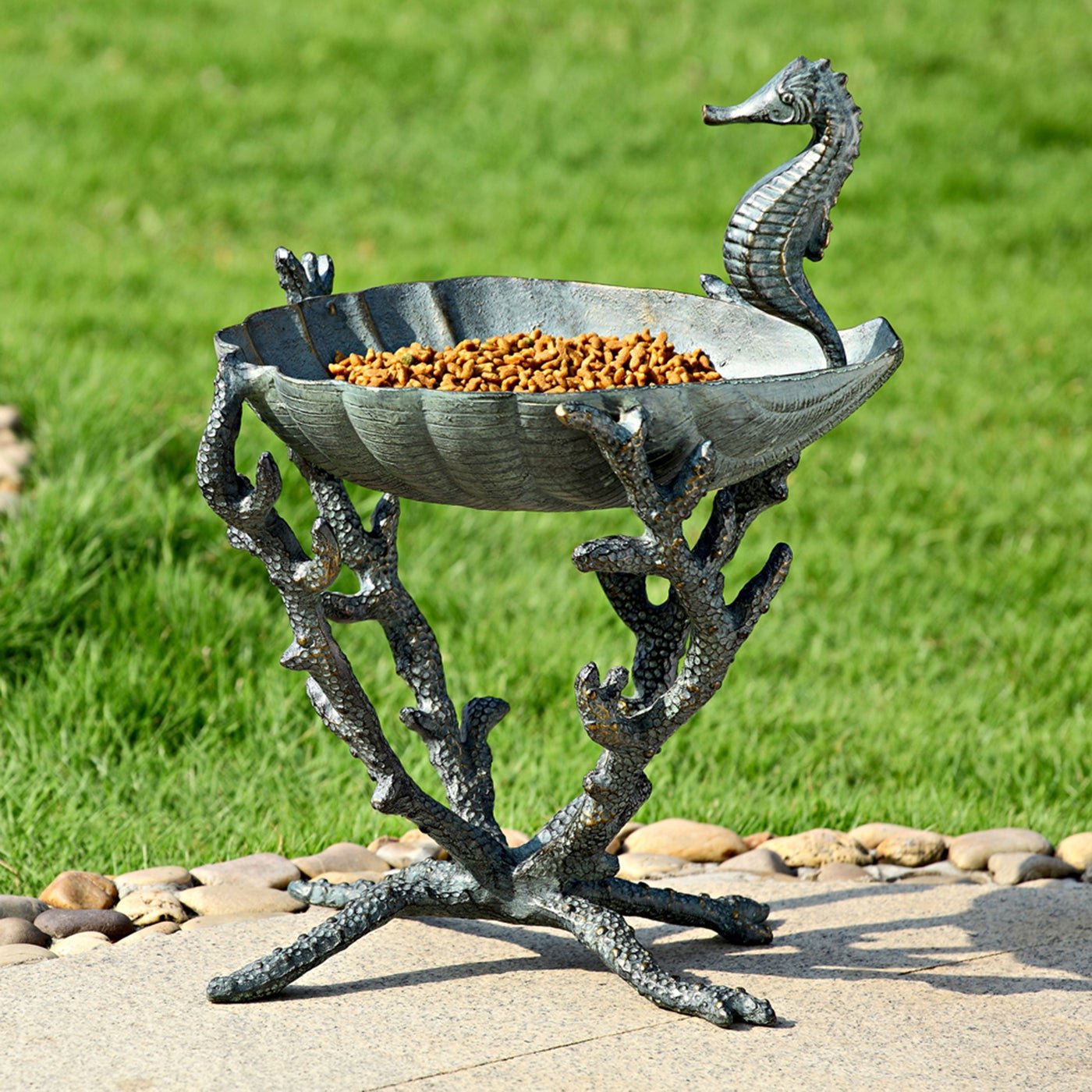 Cast aluminum seahorse birdbath with orange birdseed in the basin